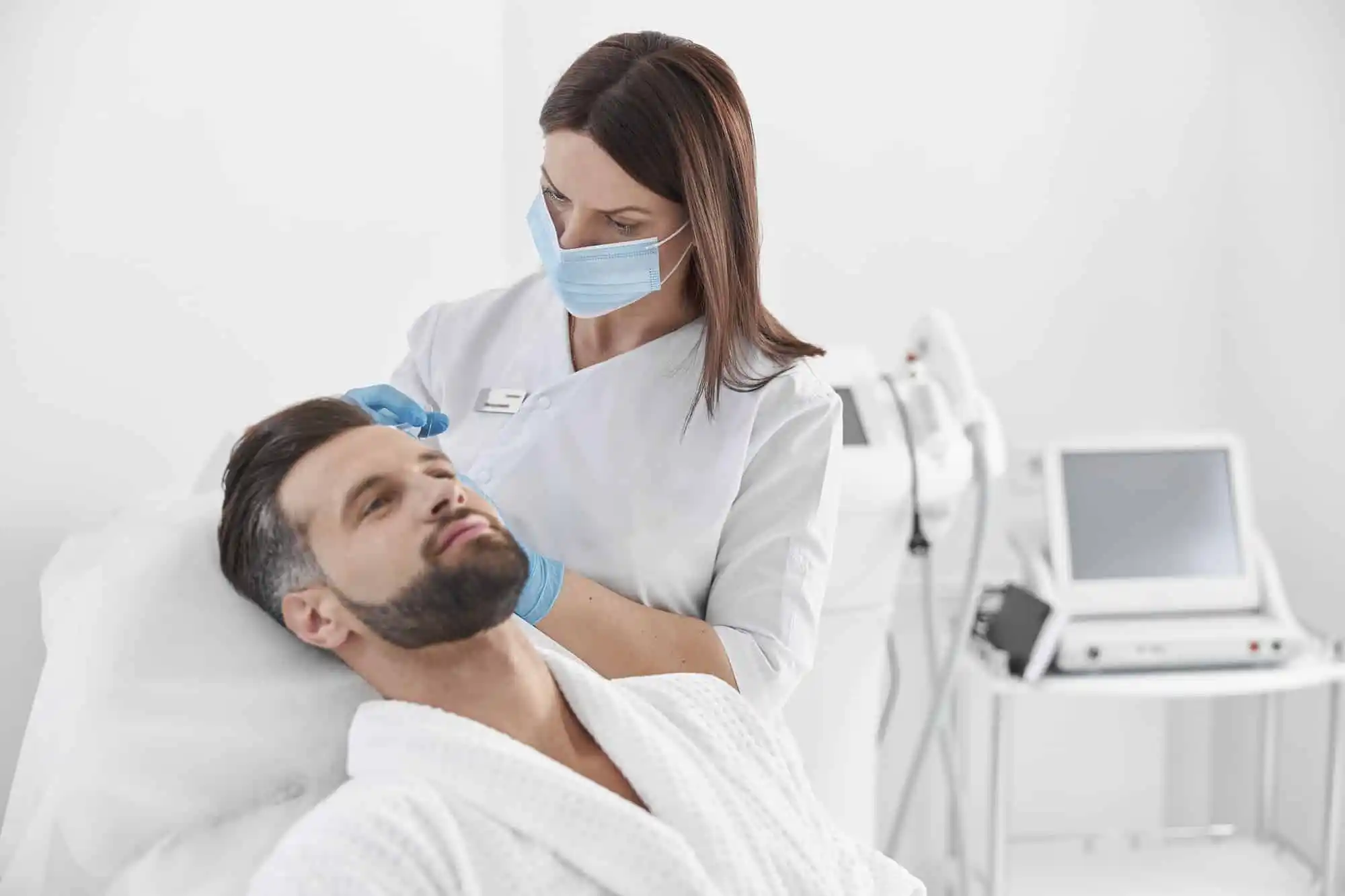 female cosmetologist with mask does injection in patient head skin at meso therapy